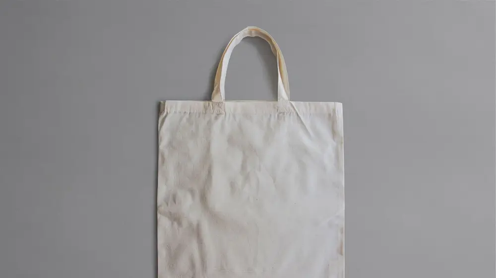 Blank natural cotton canvas tote bag with short handles, photographed flat against a grey background